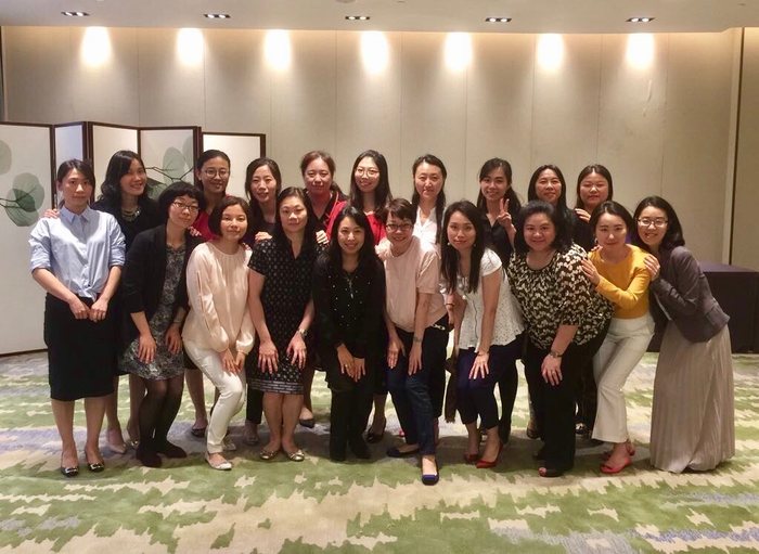 A large group of women posing together in a hall after a training session