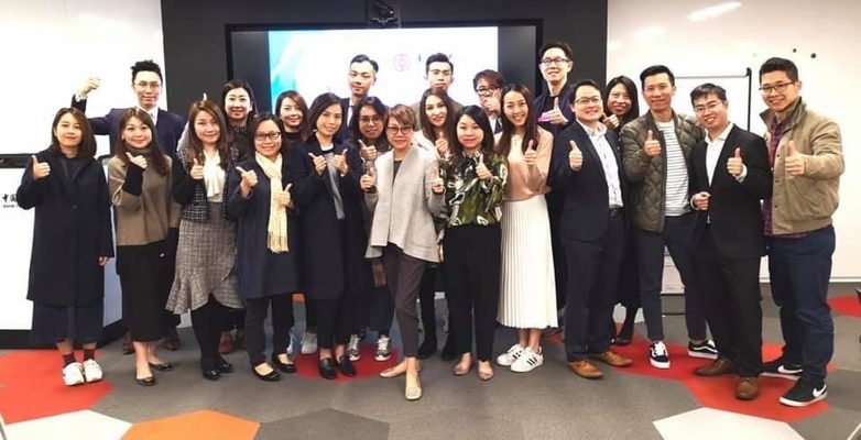 A group of workshop participants giving a thumbs up in a training room