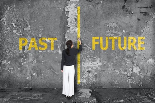A woman drawing a yellow line on a wall between the words PAST and FUTURE