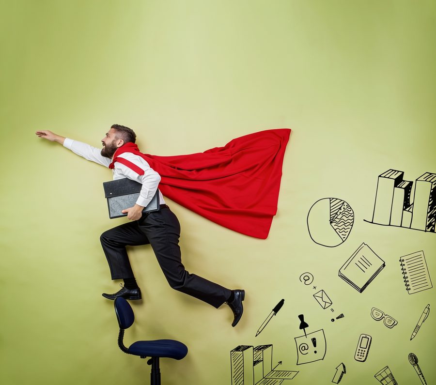 A leader in a red cape leaping from an office chair